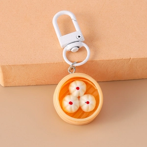 Detailed close-up of a creative dumpling steamer keychain with white lobster clasp