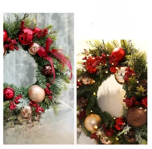 Detail of a green Christmas wreath with red berries, gold ornaments, and warm LED lights