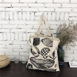 Minimalist canvas tote bag with leaf prints on a black wooden table with decor
