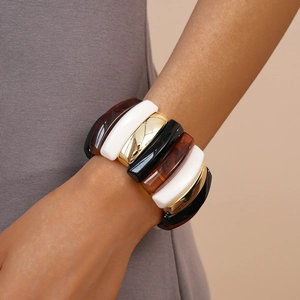 Close-up of geometric acrylic and gold metal link bracelet worn on a female wrist