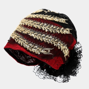 Detail of red and black turban hat with gold sequins and intricate hollow floral lace