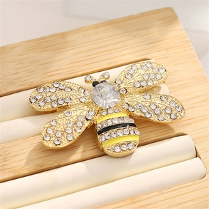 Elegant gold bee brooch with sparkling crystals and enamel stripes on a display stand