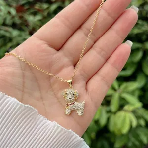 Close-up of 18K gold plated dog pendant necklace with white zircons and red bow detail