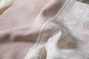 Close-up of beige woven tablecloth with intricate white geometric fringe and fabric texture