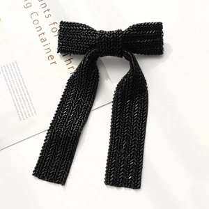 Close-up of elegant handmade black beaded bow hair clip with detailed woven texture