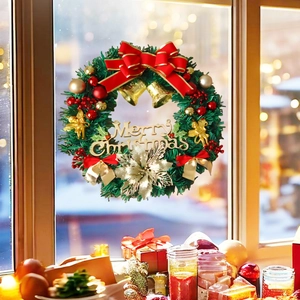 Detailed view of a Christmas wreath with gold bells and Merry Christmas lettering on a window
