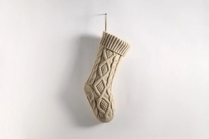 Detail of oatmeal knitted Christmas stocking featuring classic cable and diamond patterns