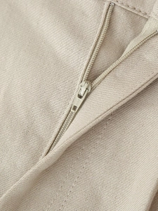 Macro shot of beige woven fabric texture and metal zipper detail on women's vest set
