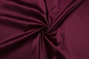 Detail of silk-like satin fabric in deep burgundy showing smooth texture and soft drape