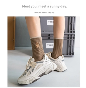 Close-up of brown ribbed mid-calf cotton socks featuring a cute small bear embroidery detail
