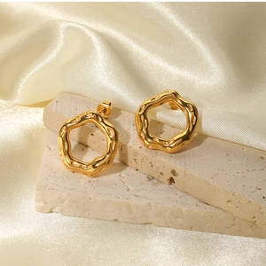 Detailed close-up of gold lava texture earrings on stone with silk background