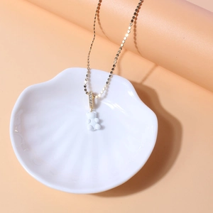 Detail of white resin gummy bear pendant on gold bead chain with zircon-set bail