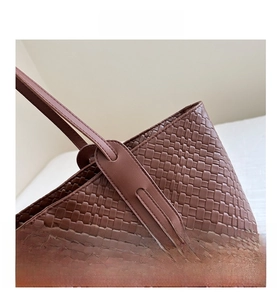 Vue détaillée d'un sac cabas marron foncé avec texture en cuir tressé et poignée solide