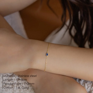 Detail of 14K gold plated stainless steel bracelet with blue square zircon on wrist