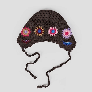 Close-up of handmade crochet flower patterns and textured knit on a dark brown vintage hat