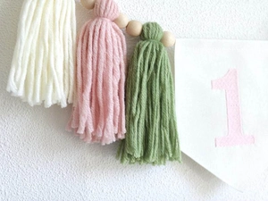 Detail of pink number 1 banner with yarn tassels and wooden beads for 1st birthday decor