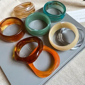 Retro wide acrylic bangles set in amber and emerald green stacked on decorative books