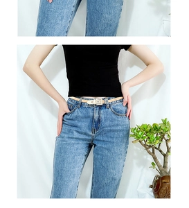 Detailed view of women thin elastic spring belt with square buckle on denim jeans