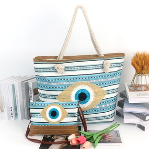 Detail of blue striped canvas tote with evil eye embroidery and rustic rope handles