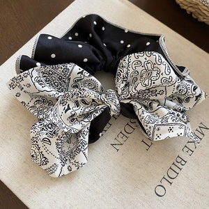 Détail d'un chouchou en satin à pois et motif paisley avec une texture douce et lisse