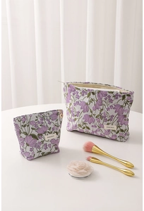 Close-up of lilac floral embroidery and brand label on textured canvas makeup bags