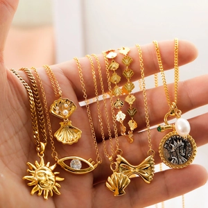 Close-up of gold plated sun and bow pendant necklaces with shell and pearl details
