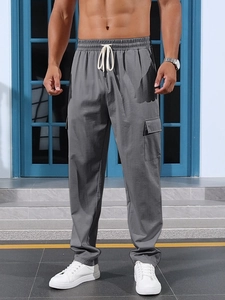 Detail of dark grey cargo pants featuring elastic drawstring waist and side flap pockets