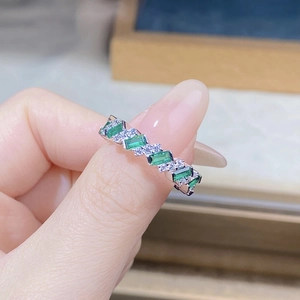 Macro shot of S925 silver ring featuring emerald cut green gem and sparkling small stones