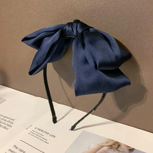 Détail d'un grand serre-tête à nœud en satin bleu avec un cerceau noir fin et élégant