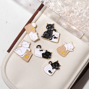 Close-up of cute black and white cat enamel pins pinned to a white canvas bag