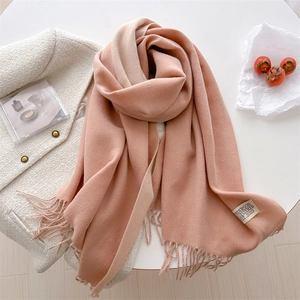 Close-up of pink and beige gradient cashmere scarf with fringe and stylish brand label