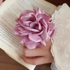 Detail eines eleganten Seidenrosen-Rings in Altrosa auf einem Spitzenhintergrund