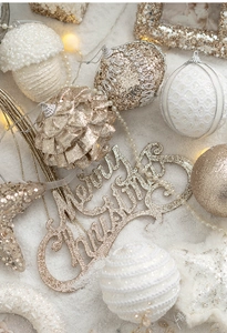 Close-up of golden and white Christmas ornaments and Merry Christmas sign on snow background