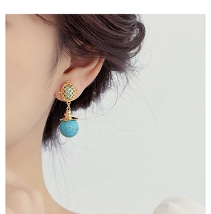 Detail view of ethnic turquoise drop earrings featuring gold hollow metal balls