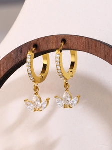 Macro shot of 18K gold plated clover earrings with zircon crystals on a wooden stand