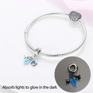 Detailed view of silver charm bracelet with glowing shell and heart clasp in dark