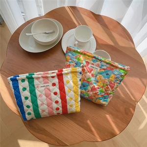 Detailed macro view of quilted cotton makeup bags with rainbow stripes and smile patterns