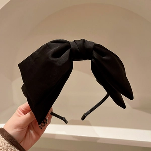 Close-up of a premium black satin headband with a large elegant bow knot design