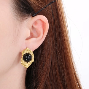 Close-up of vintage 18K gold-plated irregular earring with black bead on model's ear