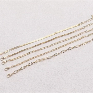 Set of five gold Bohemian Figaro and paperclip chain bracelets on grey background