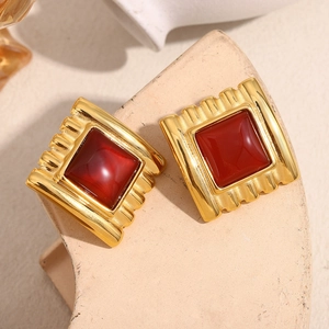 Macro detail of 18K gold plated square stud earrings with ruby red stone and ridged texture
