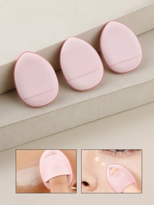 Three pink teardrop-shaped makeup puffs with finger straps on a beige stepped surface