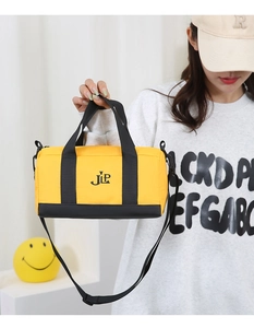 Detail of yellow nylon cylinder crossbody bag with black straps and JLP logo on model