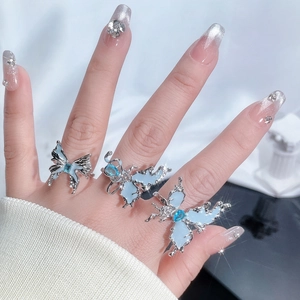Detailed view of silver butterfly rings with blue enamel and gemstones on hand