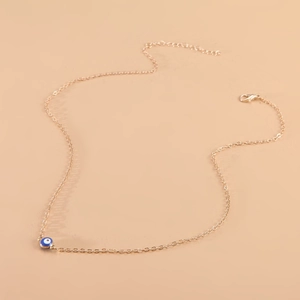 Detail view of gold O-chain necklace featuring a classic blue evil eye pendant on pink base