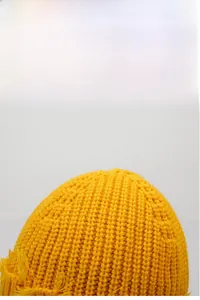 Gros plan sur la maille épaisse jaune vif et les bords effilochés du bonnet d'hiver