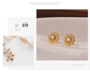 Detailed close-up of golden sunflower stud earrings with a white sparkling zircon center
