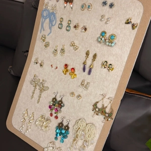 Collection of bohemian shell and tassel beaded earrings on a beige velvet display board