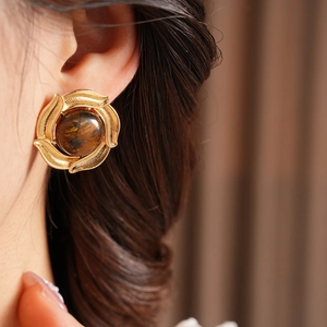 Macro shot of vintage floral stud earrings featuring brown stone inlay and gold finish