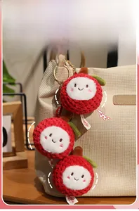 Close-up of cute plush lychee keychain with red crochet texture on a corduroy bag